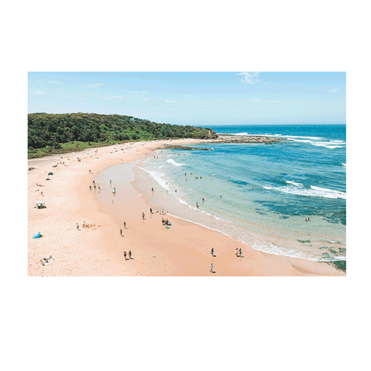 A breathtaking aerial view of Bateau Bay, NSW, featuring a crescent-shaped sandy beach, turquoise waters, and a lush green headland. The coastal landscape is dotted with beachgoers, and the waves gently lap against the rocky shoreline.
