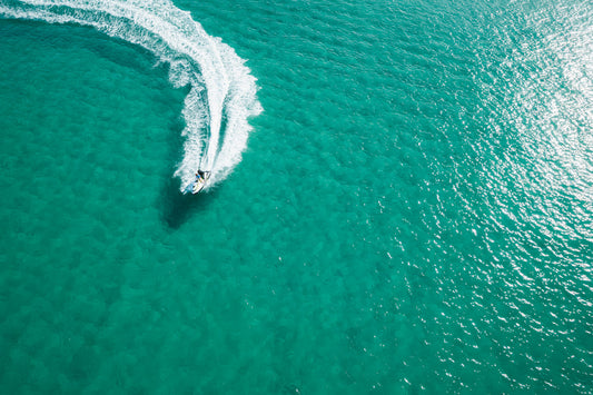 Aerial view of a jetski carving through the turquoise waters of Frazer Beach, NSW, leaving a white foam trail in its wake.
