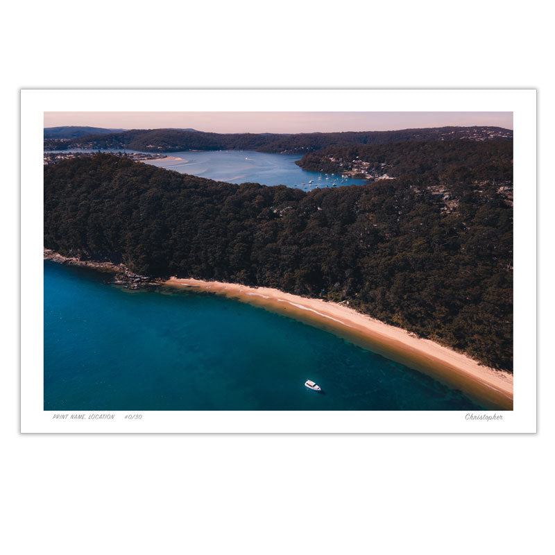 An aerial view of Lobster Beach, Central Coast, with a lone boat floating in deep blue waters, golden sandy shores, and lush green coastal headlands.
