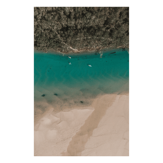 A peaceful aerial view of Corindi River flowing into Red Rock, NSW, with turquoise waters, golden sands, and boats drifting across the river.
