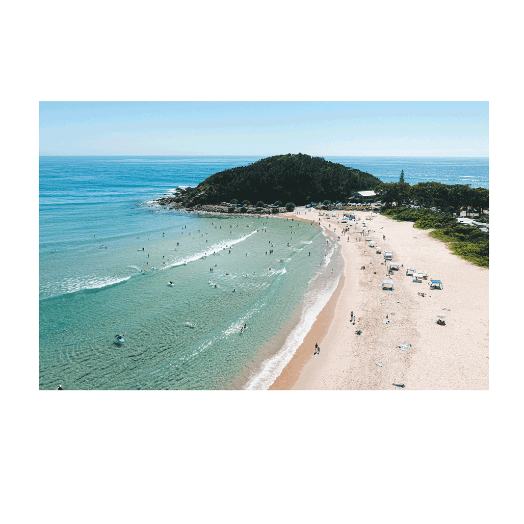 A vibrant beachside scene at Scotts Head, NSW, showcasing golden sands, turquoise waters, and beachgoers enjoying a warm summer day. Gentle waves roll onto the shore as swimmers and surfers embrace the coastal lifestyle.
