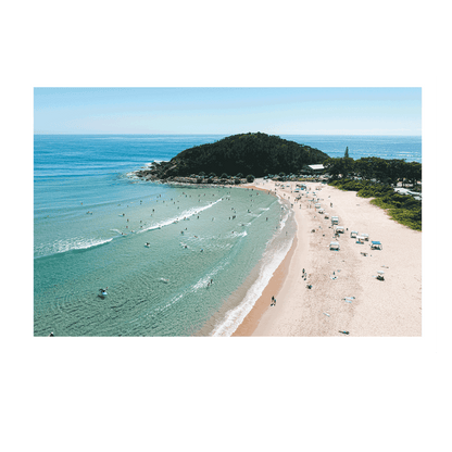 A vibrant beachside scene at Scotts Head, NSW, showcasing golden sands, turquoise waters, and beachgoers enjoying a warm summer day. Gentle waves roll onto the shore as swimmers and surfers embrace the coastal lifestyle.
