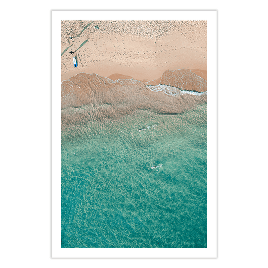 Aerial view of a lone swimmer gliding through the clear turquoise waters of Avoca Beach, NSW, with golden sand meeting the gentle ocean waves.