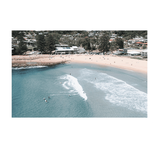 Aerial view of Avoca Beach, NSW, with surfers catching waves near the shoreline, showcasing the balance between solitude and togetherness in the ocean.