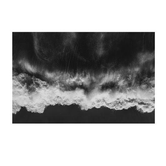 Black and white aerial view of waves crashing onto the shore at Avoca Beach, NSW, showcasing the ocean’s raw power and movement.
