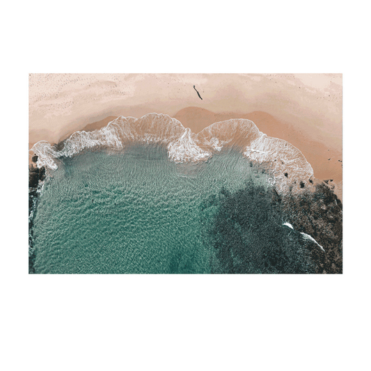 Aerial view of gentle waves meeting the golden sand at Bateau Bay, NSW, creating intricate patterns where the ocean and shoreline merge.