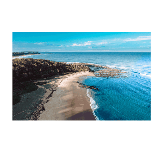 Aerial view of Bateau Bay, NSW, showcasing golden sands, deep blue ocean waves, and a serene coastal landscape bathed in natural light.