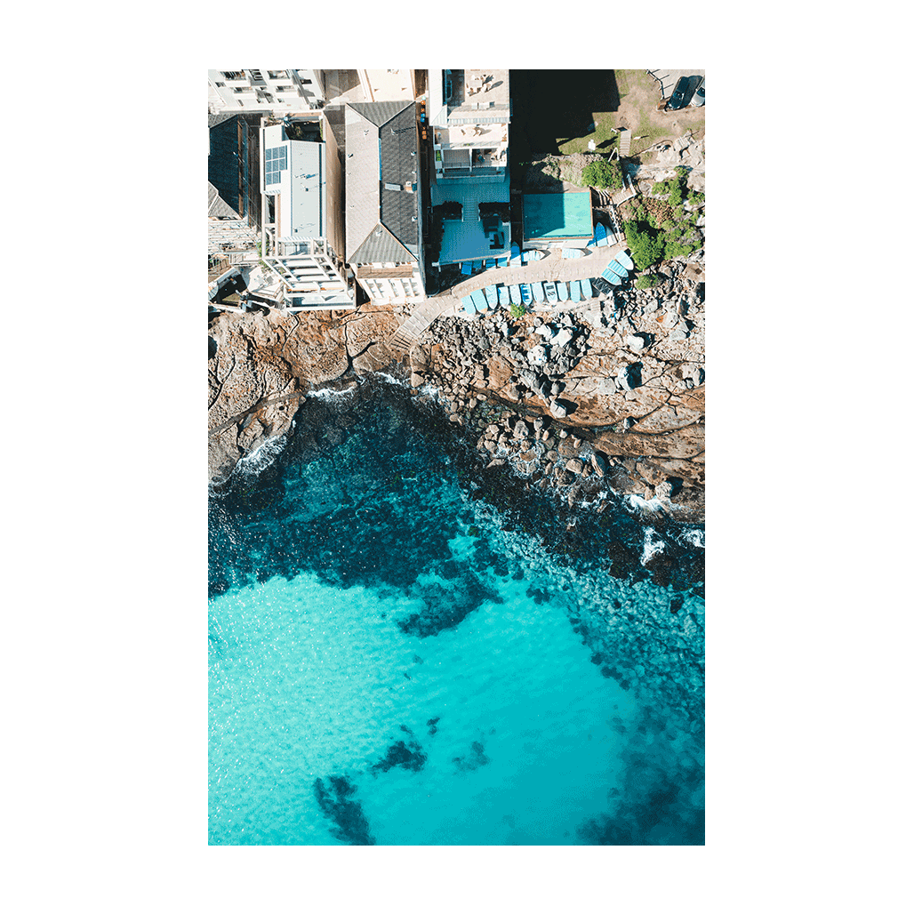 A striking aerial view of Bondi Beach, Sydney, showcasing turquoise waters, rugged cliffs, and sunlit coastal architecture.