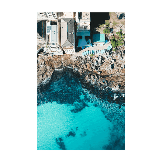 A striking aerial view of Bondi Beach, Sydney, showcasing turquoise waters, rugged cliffs, and sunlit coastal architecture.