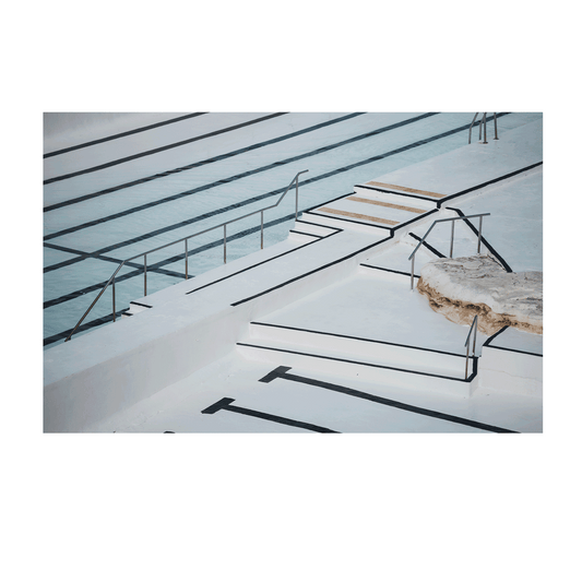 A minimalist architectural view of Bondi’s ocean pool, showcasing crisp white surfaces, geometric shadows, and deep lane markings.