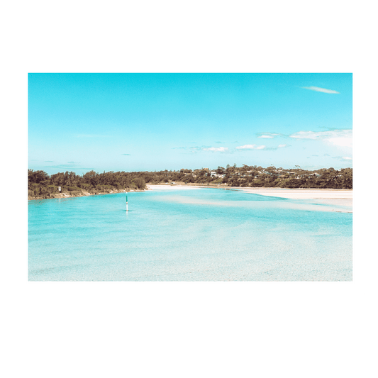 Scenic view of Broulee on the South Coast of NSW, featuring crystal-clear turquoise waters, golden sandbanks, and lush coastal greenery under a bright blue sky.