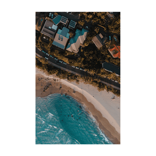 A stunning aerial print of Byron Bay, NSW, showcasing colourful beach houses, palm trees, and golden sandy shores at sunset. A perfect coastal scene.