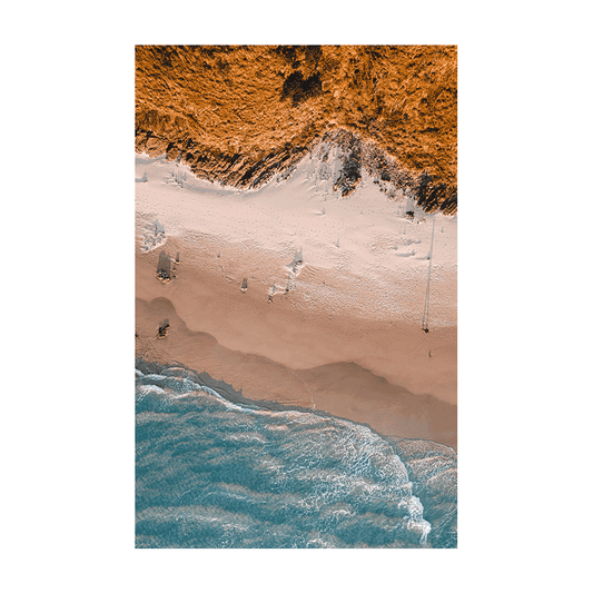 A striking aerial print of Wategos Beach, Byron Bay, NSW, showcasing golden dunes, rugged cliffs, and the deep blue ocean in a stunning coastal composition.