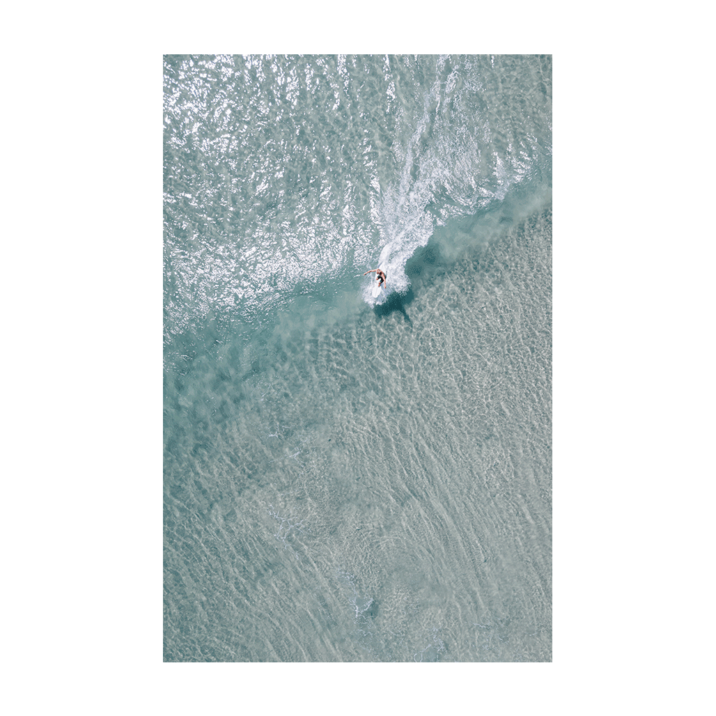 A lone surfer carves through the crystal-clear waters of Crescent Head, NSW, captured in a stunning aerial coastal print.