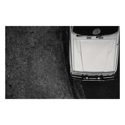 A black and white aerial photograph of a classic parked vehicle at Forresters Beach, NSW, showcasing bold contrast, texture, and symmetry.