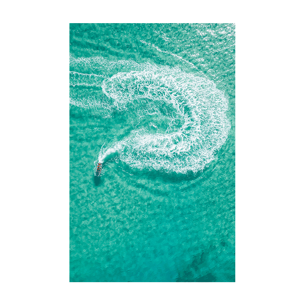 A jet ski carving a perfect swirl in the turquoise waters off Frazer Beach, NSW, leaving a foamy white trail.
