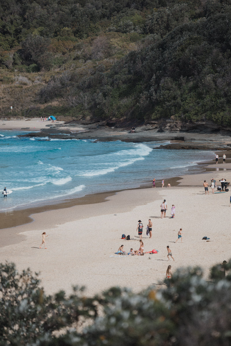 A scenic coastal print of Frazer Beach, NSW, featuring beachgoers enjoying the sun, waves, and golden sands framed by lush coastal cliffs.