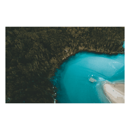 A breathtaking aerial view of Hat Head, NSW, showcasing the contrast between lush forest and vibrant turquoise coastal waters.