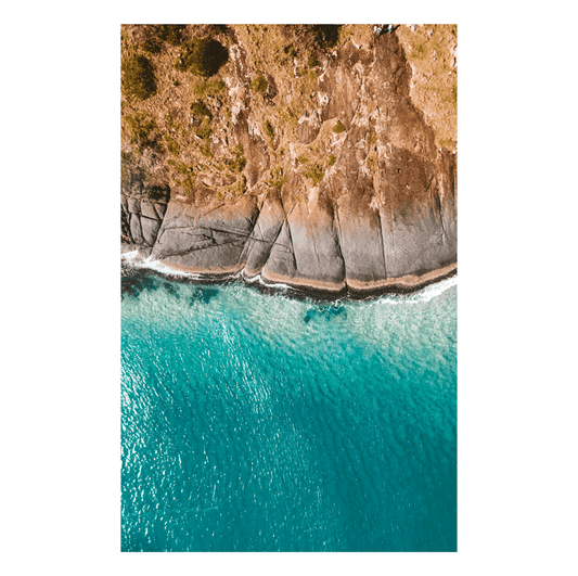 A stunning aerial view of Hat Head, NSW, featuring smooth rock formations meeting the turquoise ocean waters.