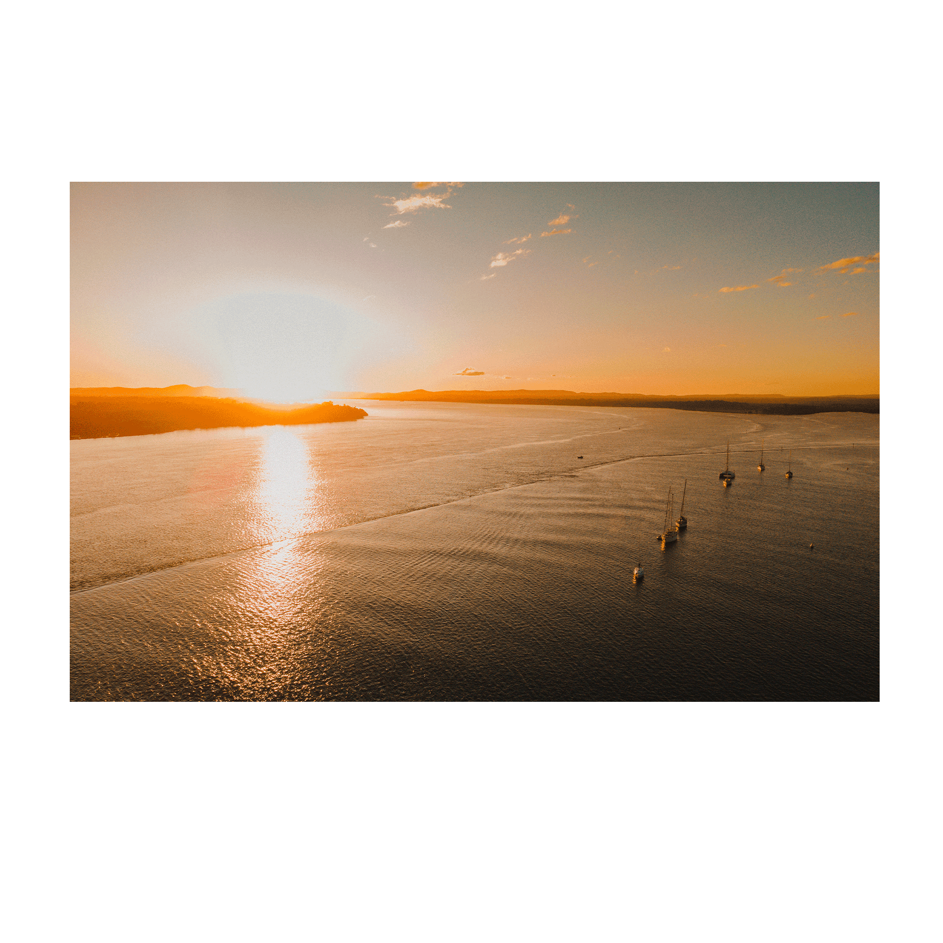 A golden sunset over calm waters in Illuka, North Coast, NSW, with boats peacefully resting in the bay.
