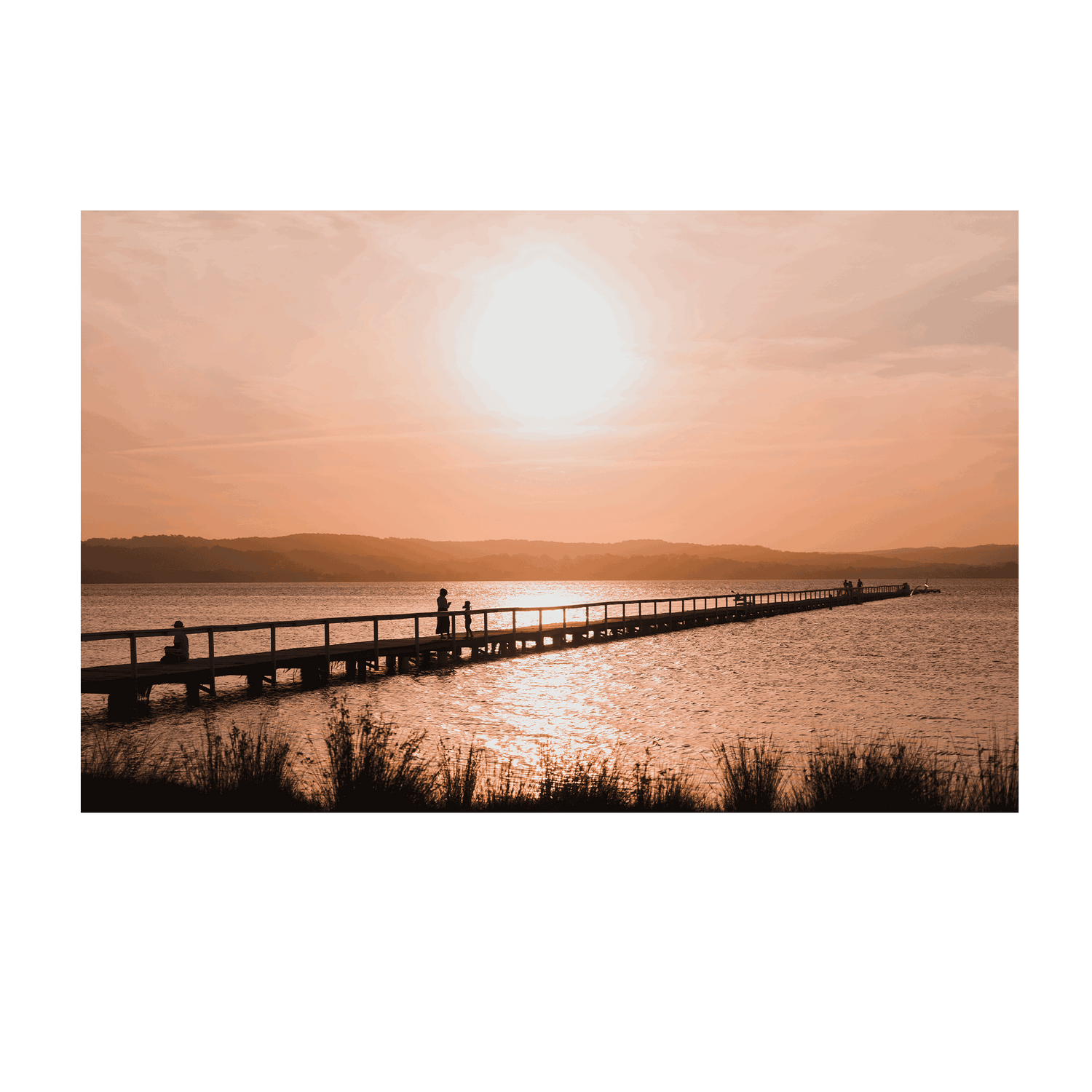 A stunning sunset at Long Jetty, NSW, with silhouettes walking along the boardwalk as golden light reflects on the water.