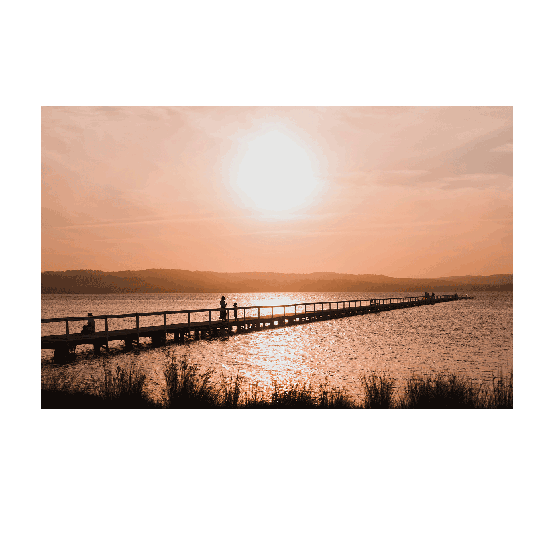 A stunning sunset at Long Jetty, NSW, with silhouettes walking along the boardwalk as golden light reflects on the water.