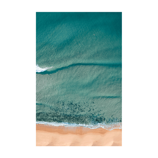 A serene aerial view of Macmasters Beach, NSW, capturing rolling waves, golden sands, and a lone swimmer floating in tranquil waters.