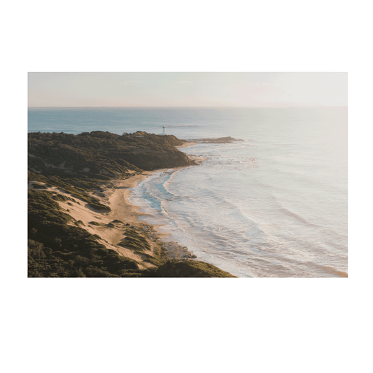 A soft, misty aerial view of Norah Head, NSW, featuring rolling sand dunes, a rugged coastline, and gentle ocean waves bathed in morning light.