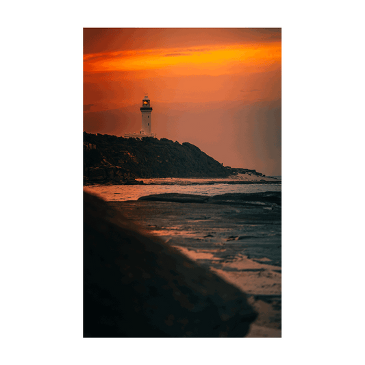 A dramatic coastal sunset at Norah Head, NSW, with a glowing magenta sky over the lighthouse and rugged coastline.