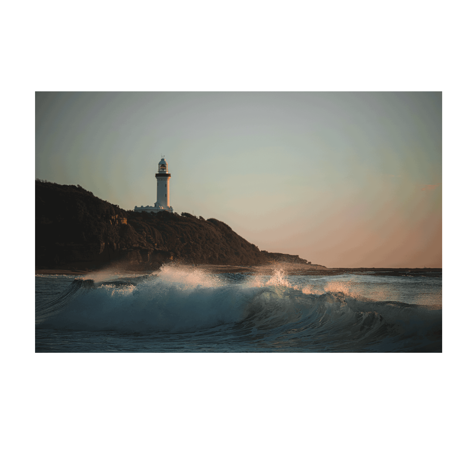 A dramatic coastal scene of Norah Head, NSW, featuring powerful waves crashing beneath the lighthouse at sunset.