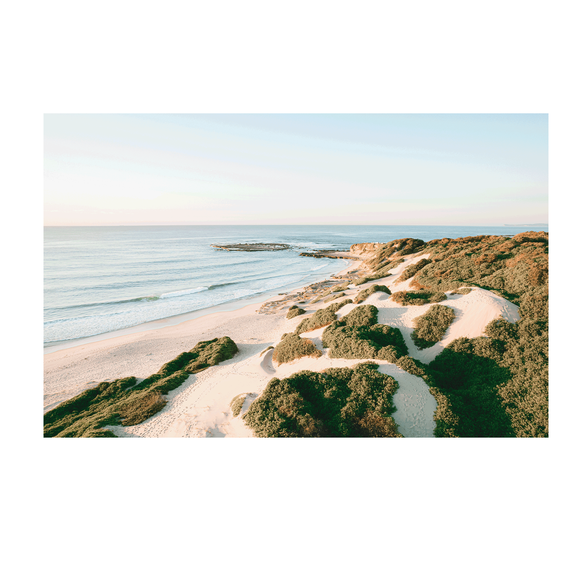 A breathtaking aerial view of Soldiers Beach, Norah Head, NSW, highlighting golden sand dunes rolling towards the tranquil ocean.