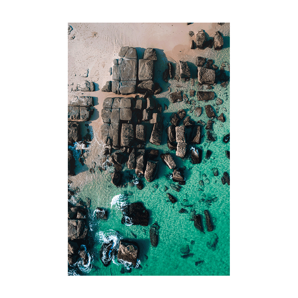 A stunning aerial view of Soldiers Beach, Norah Head, NSW, showcasing rugged rock formations blending into crystal-clear turquoise waters.