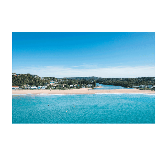 Aerial view of North Avoca Beach, NSW, showcasing turquoise ocean waters, golden sandy shores, and the winding lagoon framed by lush greenery.