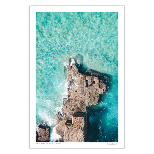 Aerial view of North Avoca Rocks, NSW, featuring a school of fish passing by the coast line in the crystal-clear waters, surrounded by the serene rocky coast.