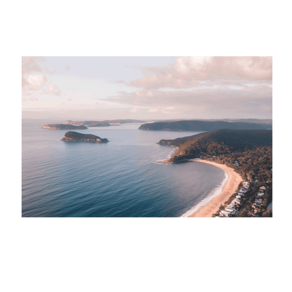 A breathtaking aerial view of Pearl Beach and Lion Island, NSW, with golden sunlight casting a warm glow over the coastline and tranquil blue waters.