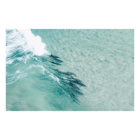 A stunning aerial view of a pod of dolphins surfing through the turquoise waters of Sandbar, Forster, NSW.