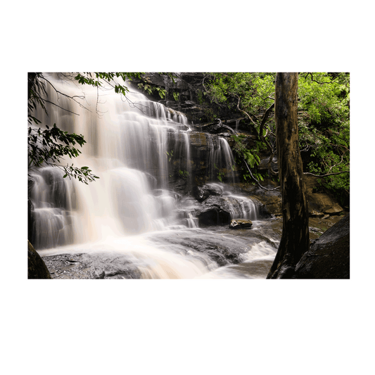 A stunning waterfall scene at Somersby Falls, Central Coast, featuring a silky cascading flow over rugged rocks, framed by lush rainforest greenery.
