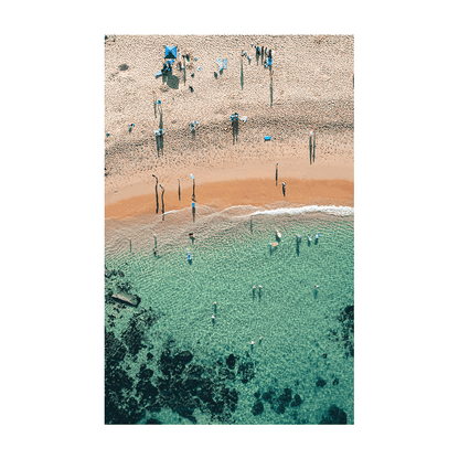 An aerial view of Spoon Bay, Central Coast, featuring beachgoers enjoying crystal-clear turquoise waters and golden sands under bright summer sunshine.