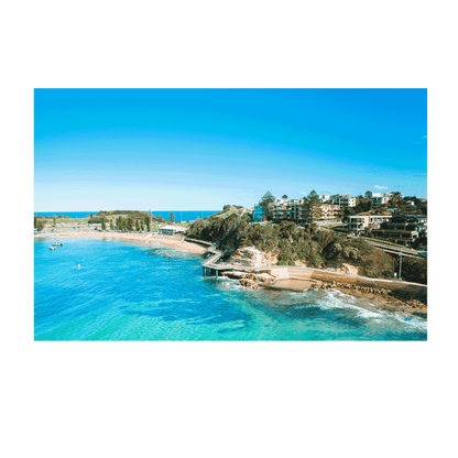 An aerial view of Terrigal Beach, NSW, showcasing the vibrant blue ocean, a winding coastal walkway, and the picturesque beachside community.
