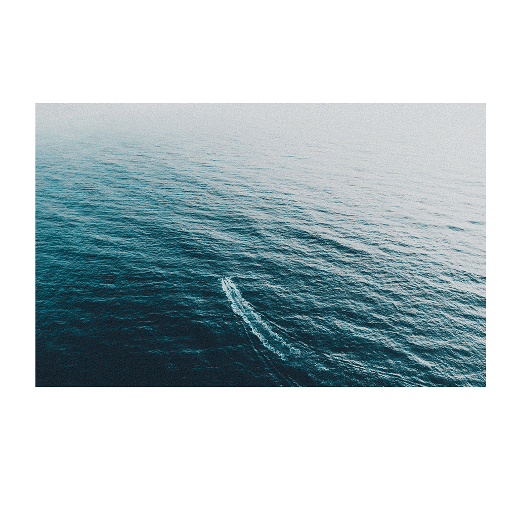 Aerial view of a vast deep blue ocean with a single vessel leaving a gentle wake behind, creating a sense of solitude and serenity.