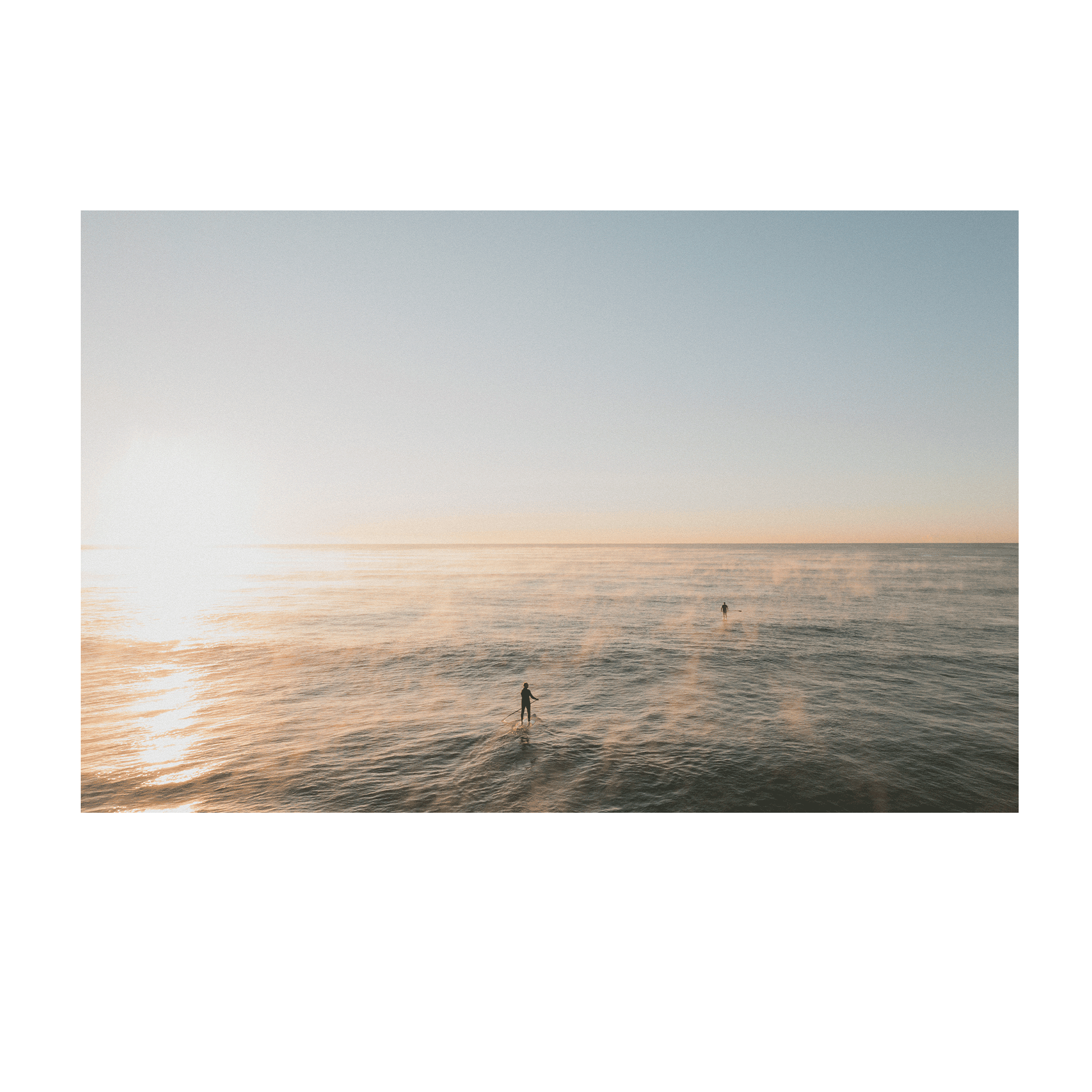 A peaceful ocean scene at Terrigal Beach, NSW, where mist rises from the water as paddleboarders move across the calm sea at sunrise.
