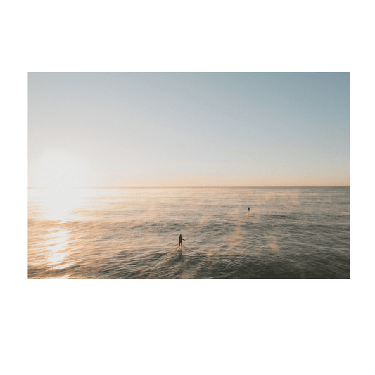 A peaceful ocean scene at Terrigal Beach, NSW, where mist rises from the water as paddleboarders move across the calm sea at sunrise.
