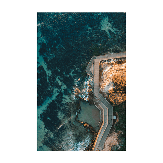 Aerial view of Terrigal’s boardwalk and ocean pool, curving along the rugged coastline with deep blue ocean waters surrounding it.
