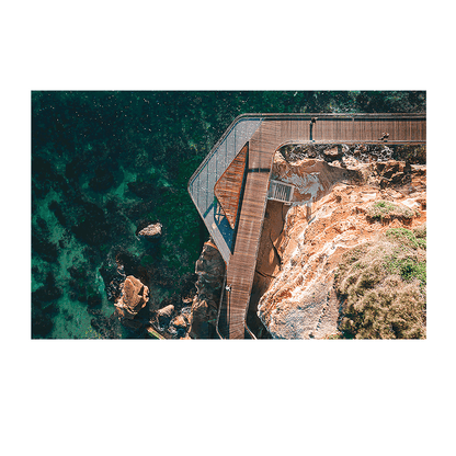 An aerial view of the Terrigal boardwalk, showing its elegant curves over the rocky coastline with turquoise ocean waters below.