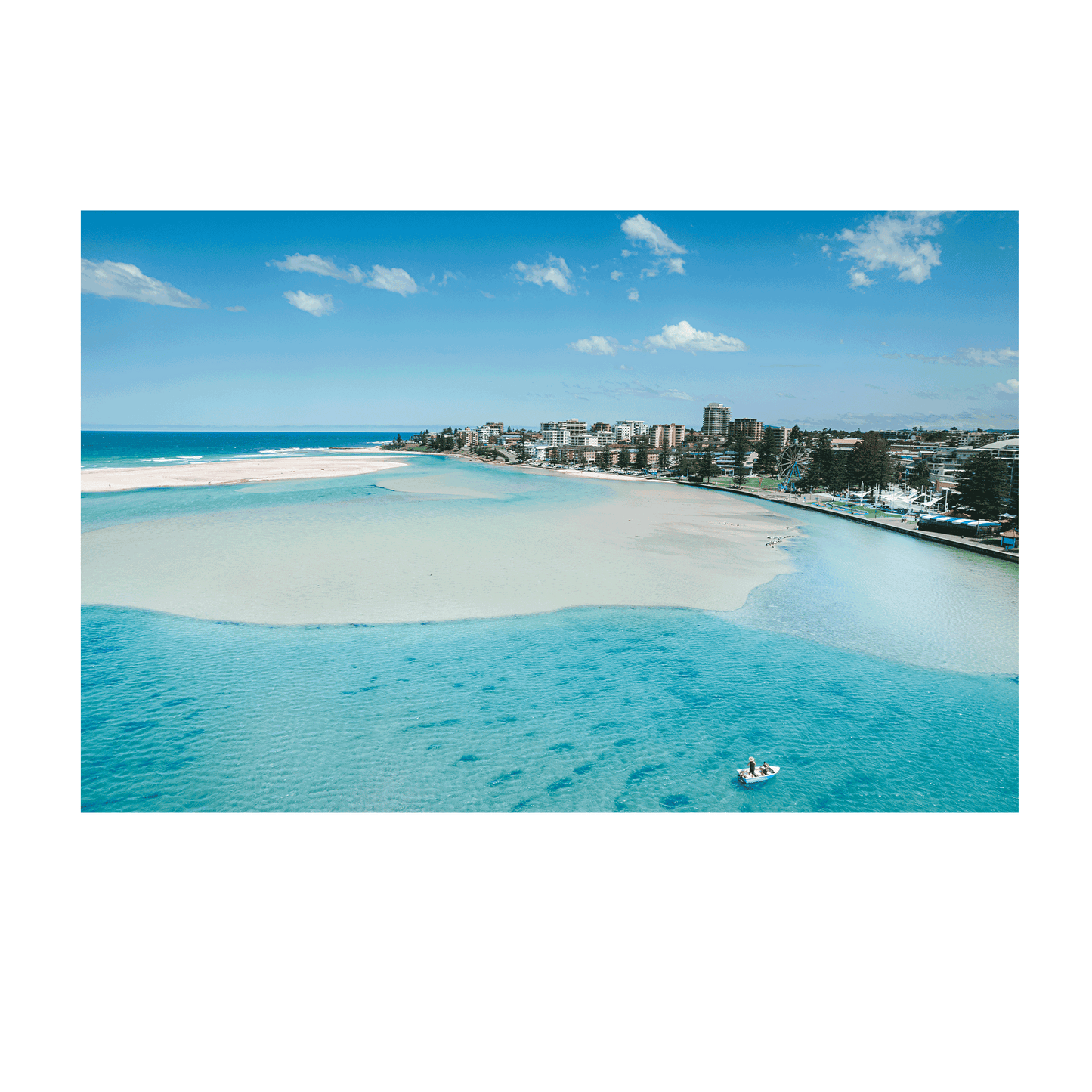 A stunning aerial print of The Entrance, NSW, featuring a small boat drifting on turquoise waters near golden sandbanks, with a scenic coastal backdrop.
