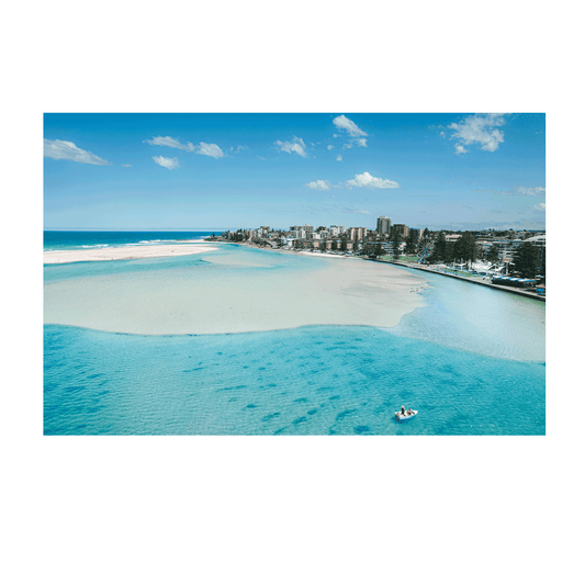 A stunning aerial print of The Entrance, NSW, featuring a small boat drifting on turquoise waters near golden sandbanks, with a scenic coastal backdrop.
