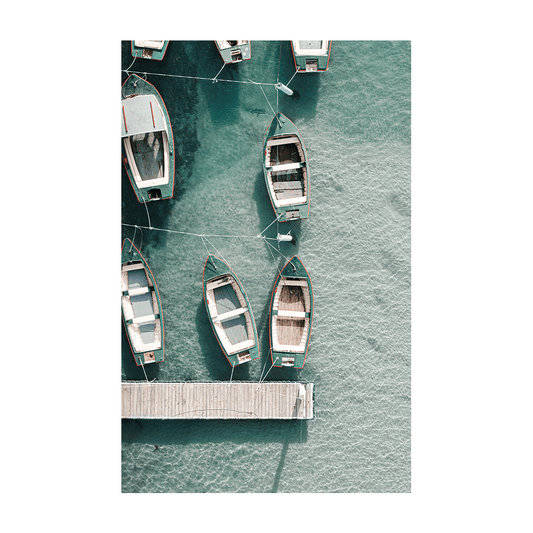 A serene aerial print of wooden boats moored to a jetty at The Entrance, NSW, floating on crystal-clear turquoise waters with soft shadows on the seabed.