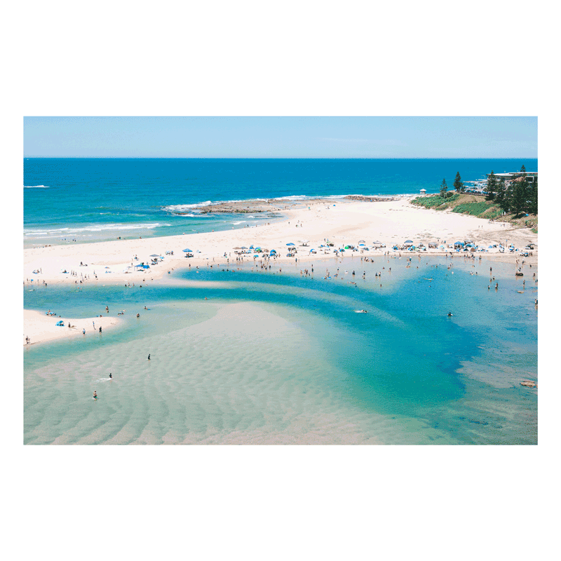 A stunning aerial print of The Entrance, NSW, featuring golden sands, turquoise waters, and vibrant umbrellas lining the shoreline on a perfect summer’s day.