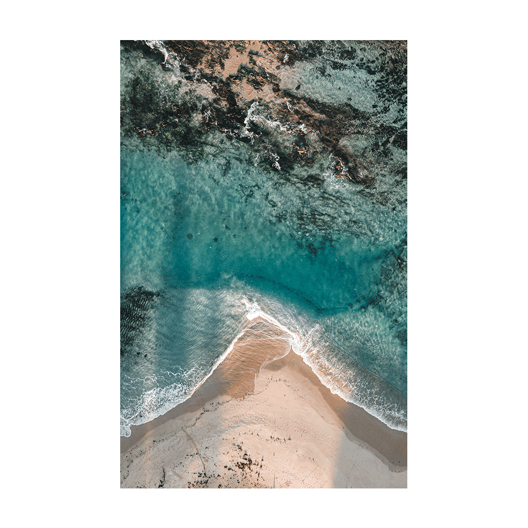 Aqua blue water of Toowoon Bay beach making pathways between the rocks and sand .