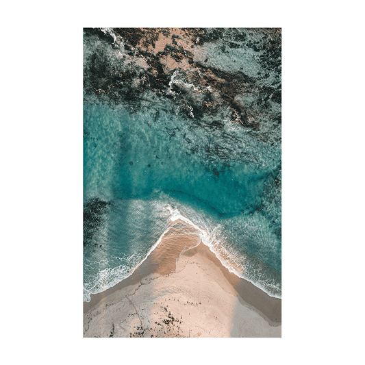 Aqua blue water of Toowoon Bay beach making pathways between the rocks and sand .